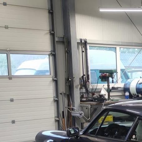 Werkstattinnenraum mit klassischem Porsche 911 vor dem Hallentor